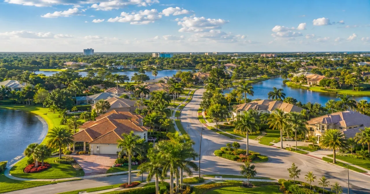 Aerial view of a Florida residential community with lakes, palm-lined streets, and tile-roof homes