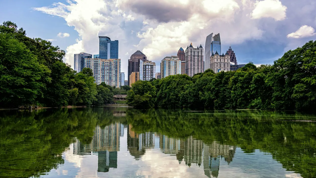 The Midtown Atlanta, Georgia skyline reflected in Lake Clara Meer at Piedmont Park, framed by green trees