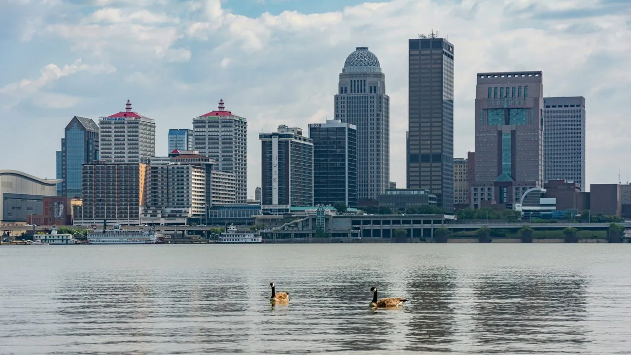 The downtown Louisville, Kentucky skyline seen across the Ohio River, with riverboats docked along the waterfront