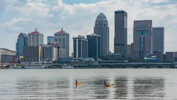 The downtown Louisville, Kentucky skyline seen across the Ohio River, with riverboats docked along the waterfront