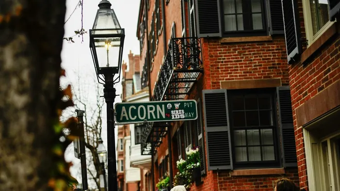 Acorn Street sign and a gas lamp among red brick rowhouses in the Beacon Hill neighborhood of Boston, Massachusetts