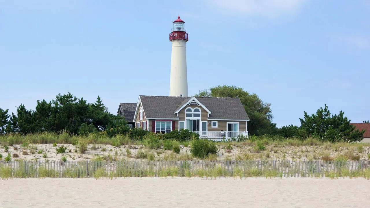 The Cape May Lighthouse rising above a beach house and dune grass in Cape May, New Jersey
