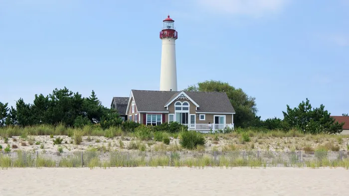 The Cape May Lighthouse rising above a beach house and dune grass in Cape May, New Jersey