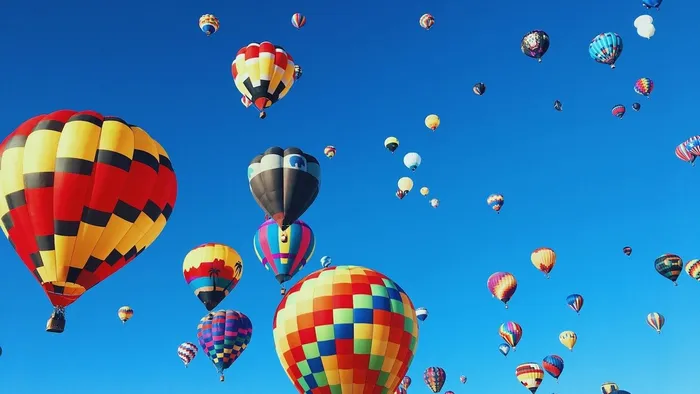 Colorful hot air balloons rising into a clear blue sky over Albuquerque, New Mexico