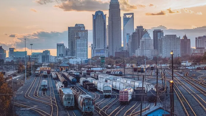 The Charlotte, North Carolina skyline at sunset, rising behind a downtown rail yard