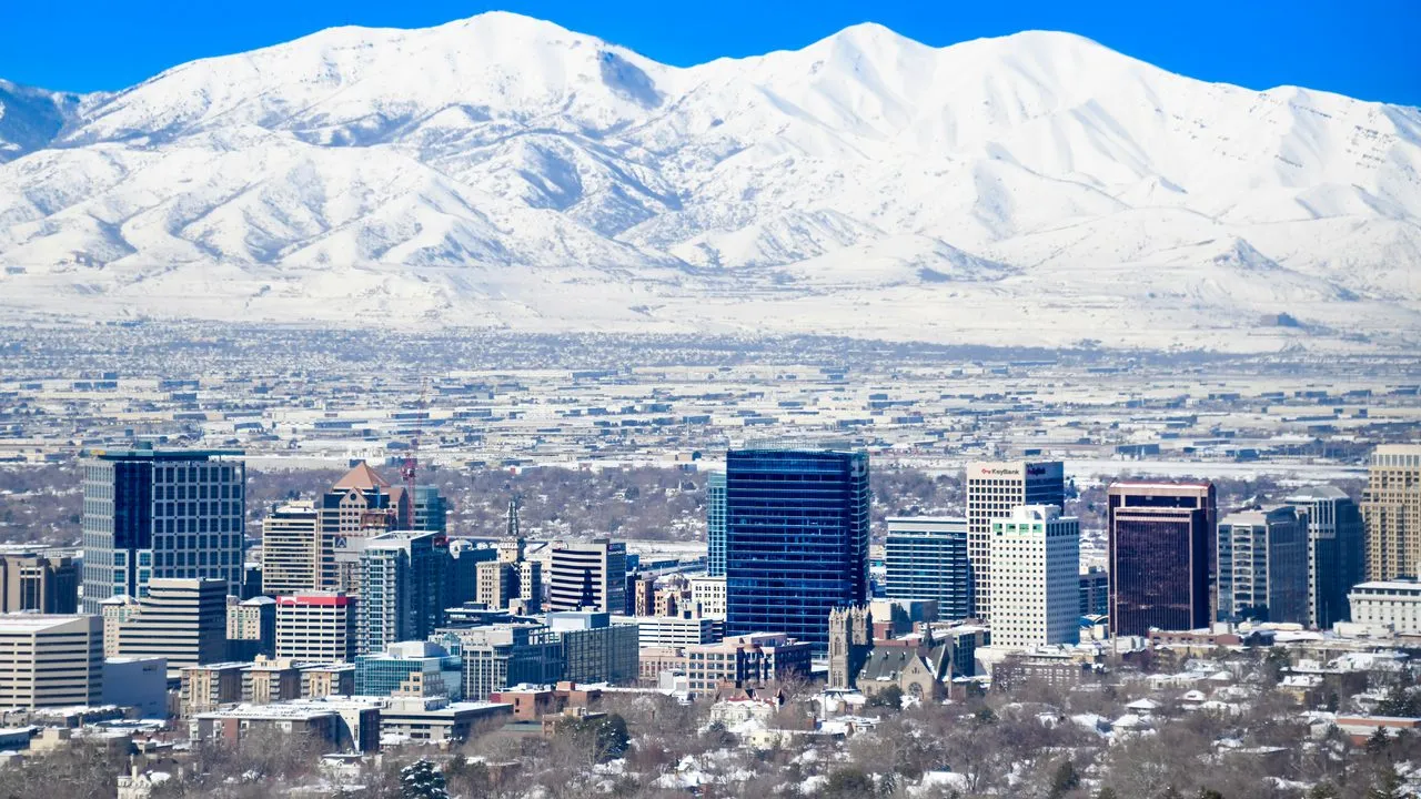 The downtown Salt Lake City skyline beneath snow-covered mountains on a clear winter day