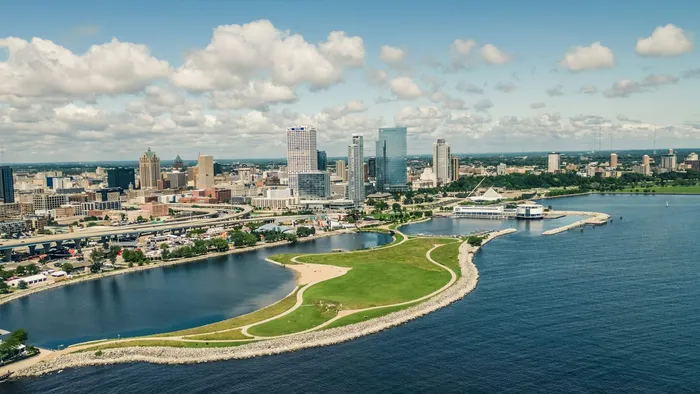 An aerial view of downtown Milwaukee, Wisconsin from over Lake Michigan, with lakefront parkland in the foreground